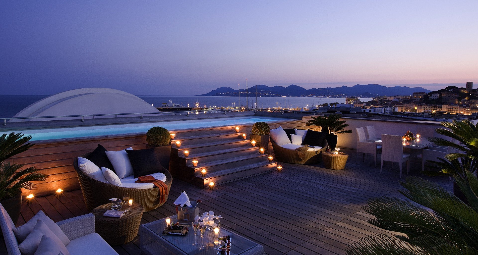 Rooftop avec piscine au crépuscule face à la baie